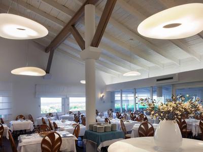 Modernes Restaurant mit hellen Deckenleuchten, Holzbalken und dekorativen Blütenarrangements.