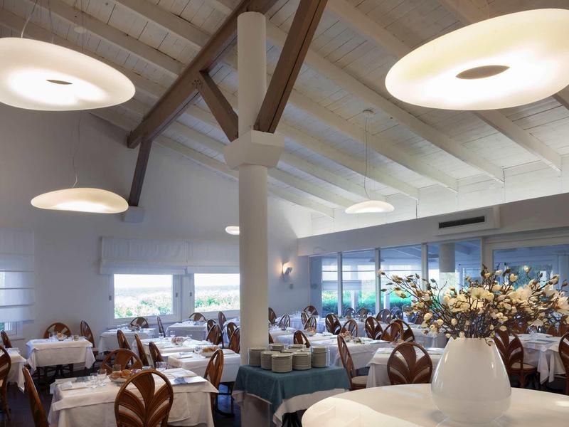 Modernes Restaurant mit hellen Deckenleuchten, Holzbalken und dekorativen Blütenarrangements.