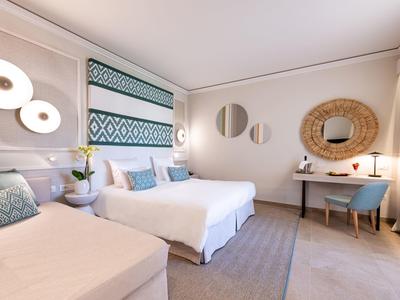 Helles, modernes Schlafzimmer mit zwei Doppelbetten, runden Spiegeln und hellblauen Akzenten.