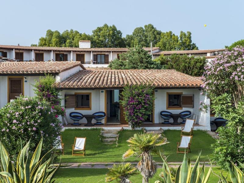 Hotelgebouw met terras en tuin, ingericht met stoelen en parasols.