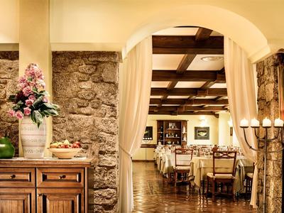 Rustic hotel restaurant with wooden tables, stone walls, and warm lighting.