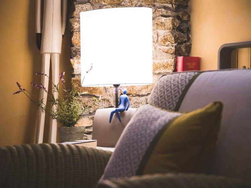 Cozy living room with sofa, cushions, lamp, and stone wall in the background.
