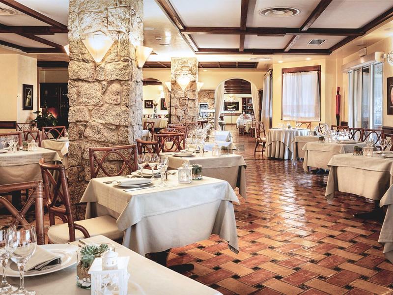 Cozy restaurant with wooden furniture, stone pillars, and warm lighting.