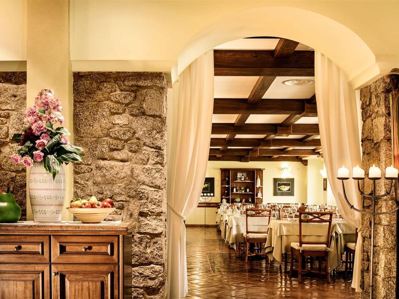 Rustic hotel restaurant with wooden tables, stone walls, and warm lighting.