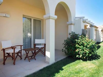 Taras z dwoma krzesłami i małym stolikiem przed domkiem wakacyjnym w słoneczny dzień