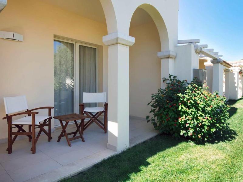 Taras z dwoma krzesłami i małym stolikiem przed domkiem wakacyjnym w słoneczny dzień