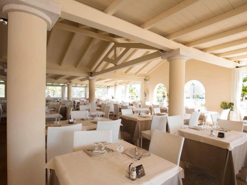 Jasna, otwarta restauracja z białymi stolikami i krzesłami w hotelu wakacyjnym.