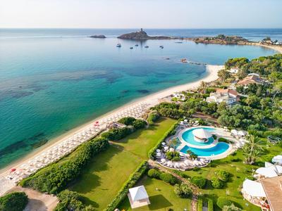 Widok z lotu ptaka hotelu przy plaży z basenem i zielonymi trawnikami.