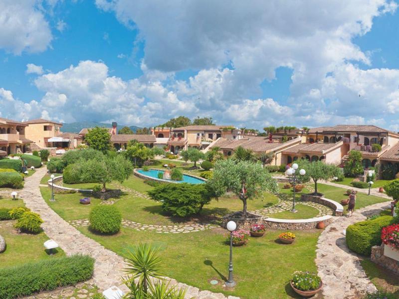 Große Gartenanlage mit vielen Wegen, grünen Büschen und mediterranen Häusern unter blauem Himmel.