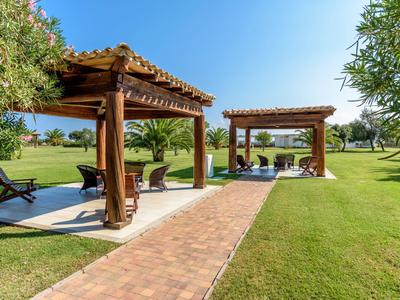 Zwei Holzpavillons mit Liegestühlen auf einem gepflegten Rasen unter klarem blauem Himmel.
