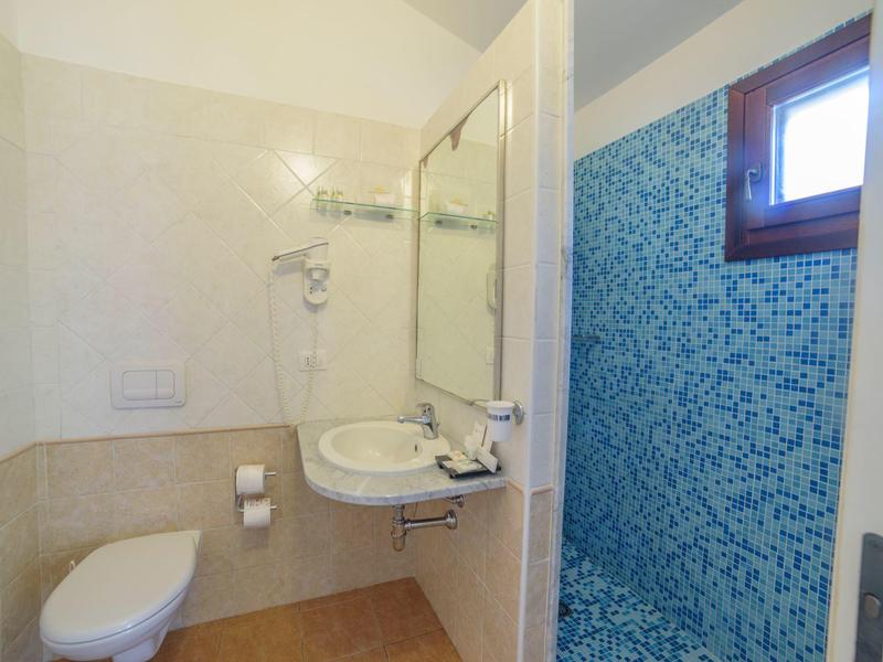 Kleines Badezimmer mit Toilette, Waschbecken und separater Dusche mit blauen Mosaikfliesen.