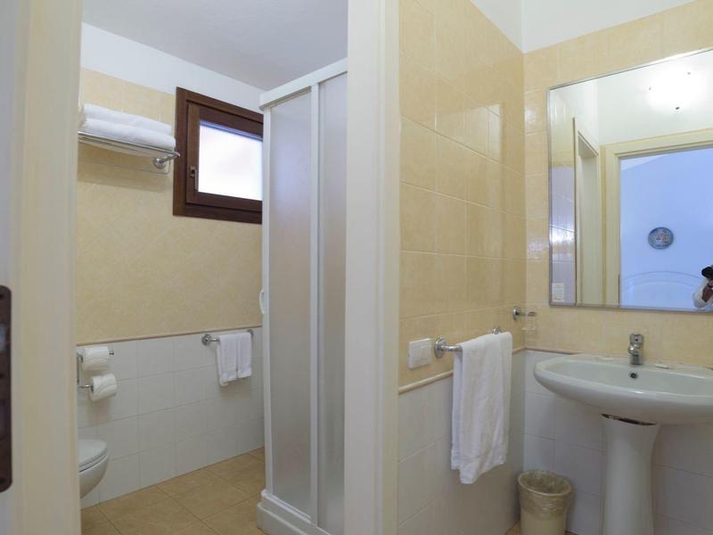 Kleines Badezimmer mit Duschkabine, Waschbecken, Spiegel und Handtüchern in hellen Farbtönen.