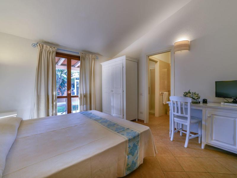 Helles Hotelzimmer mit Doppelbett, Schreibtisch, TV und Balkon mit Blick ins Grüne.