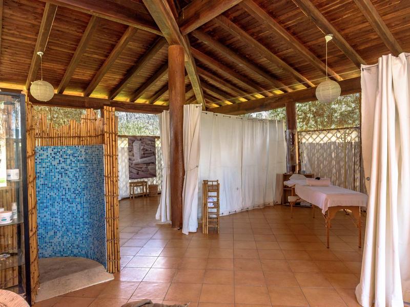 Geräumiger Wellnessraum mit Massageliegen und Vorhängen unter Holzdach