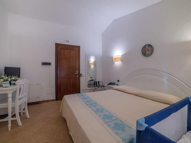 Hell eingerichtetes Hotelzimmer mit Doppelbett, Nachttischen und einem kleinen Tisch mit Stühlen.