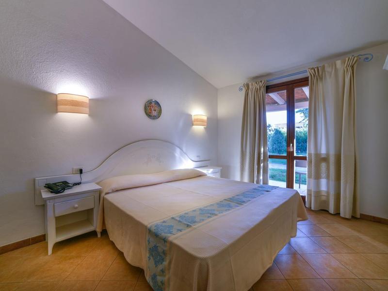 Schlafzimmer mit Doppelbett, Nachttischen und Balkon mit Blick auf die Berge.