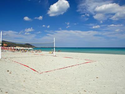 Plage de sable blanc avec filet de volley, ciel bleu et mer turquoise calme