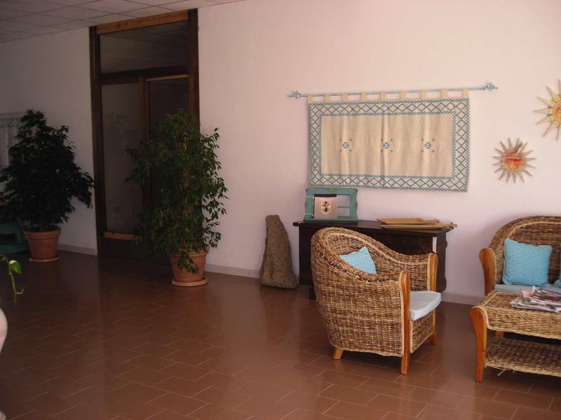 Hall d'hôtel confortable avec mobilier en osier, plantes et décorations murales claires en arrière-plan.