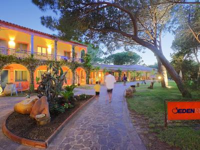 Abendansicht eines Hotels mit beleuchtetem Weg und grüner Gartenanlage.