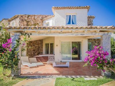 Rekreační dům s kamennými zdmi, verandou a posezením, obklopený květinami a zahradou.