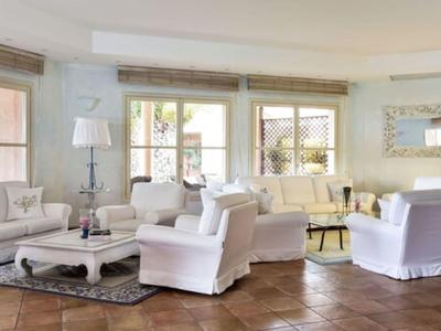 Helle Wohnzimmerlounge mit weißen Sesseln, Holzboden und großen Fenstern.