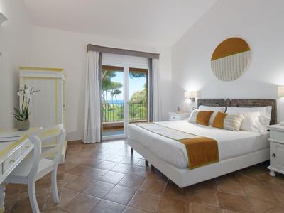 Moderne hotelkamer met tweepersoonsbed, bureau en balkon met uitzicht op de tuin.