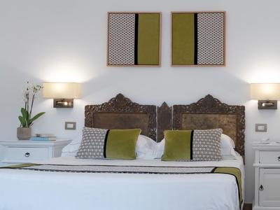 Modern ingericht hotelkamer met tweepersoonsbed, nachtkastjes en decoratieve schilderijen aan de muur.