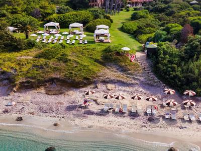 Strand met parasols, ligbedden en cabana's voor een bebost hotel.