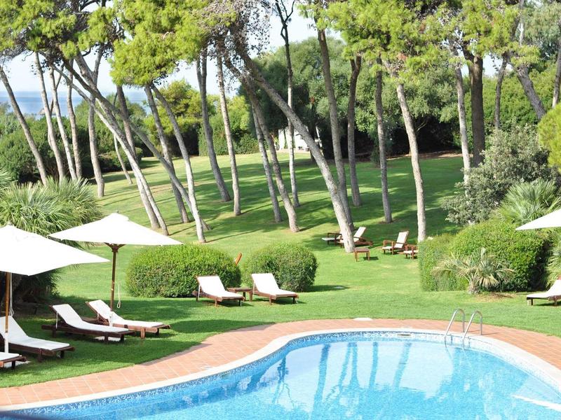 Leisure area with blue pool, white loungers, umbrellas, and green garden setting