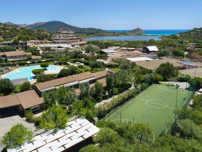 Vue d'un complexe hôtelier avec piscine, terrain de football et paysage verdoyant près de la côte.