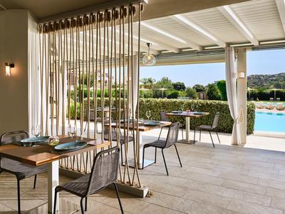 Terrasse d'hôtel couverte avec espace repas, vue sur la piscine et le paysage.