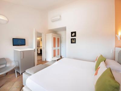 Chambre d'hôtel moderne avec grand lit, TV et balcon avec vue.