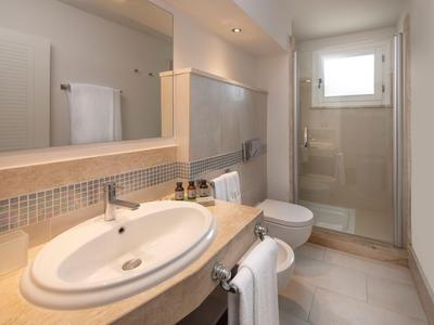 Salle de bain d'hôtel moderne avec lavabo, toilettes et cabine de douche dans un design lumineux.