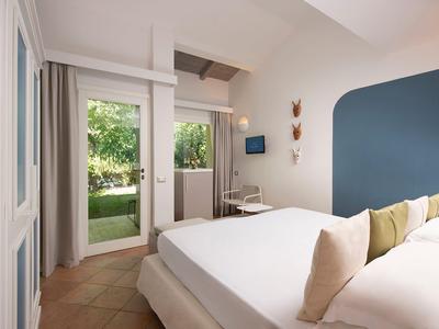 Chambre d'hôtel moderne avec lit double, accents bleus et vue sur le jardin.