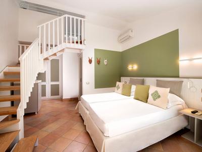 Chambre d'hôtel moderne avec lit double, mur d'accent vert et escalier.