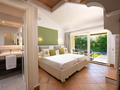 Chambre d'hôtel lumineuse avec lit double et vue sur un jardin avec piscine.
