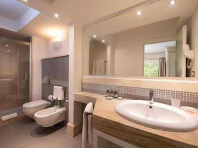 Salle de bain moderne avec douche, toilette, bidet et grand miroir dans des tons chauds.