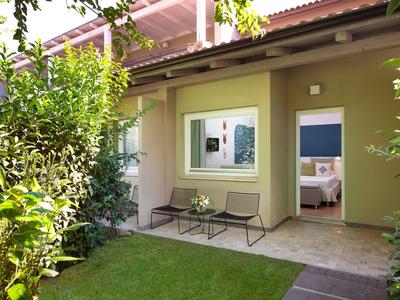 Maison avec terrasse, jardin, plantes vertes et un banc.