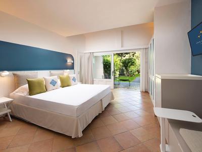 Chambre d'hôtel moderne avec lit double, balcon et vue sur le jardin.