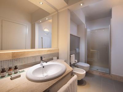 Salle de bain moderne avec lavabo, miroir, bidet et douche aux tons beige doux.