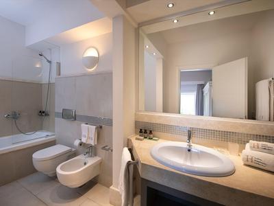 Salle de bain moderne avec baignoire, bidet, WC et lavabo aux tons neutres.
