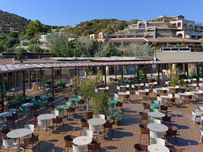 Grande terrasse d'hôtel avec de nombreuses tables et chaises, entourée de montagnes et d'un ciel bleu.