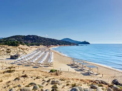 Plage avec rangées de transats et parasols au bord d'une mer calme sous un ciel dégagé.