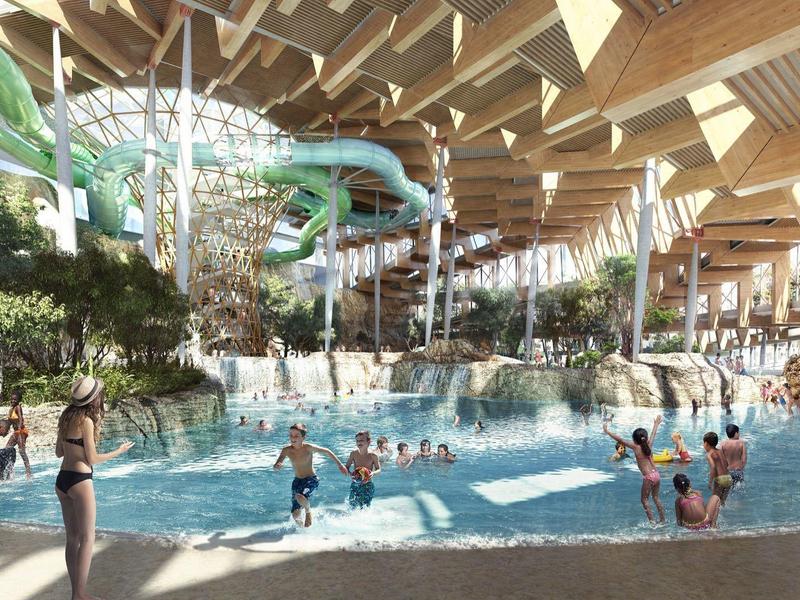 Large indoor pool with water slides and many swimmers in a tropical setting.