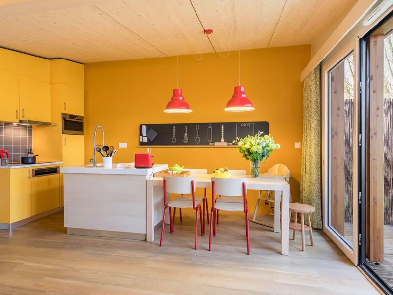 Modern dining area and kitchen with yellow walls and large sliding glass doors to the garden.
