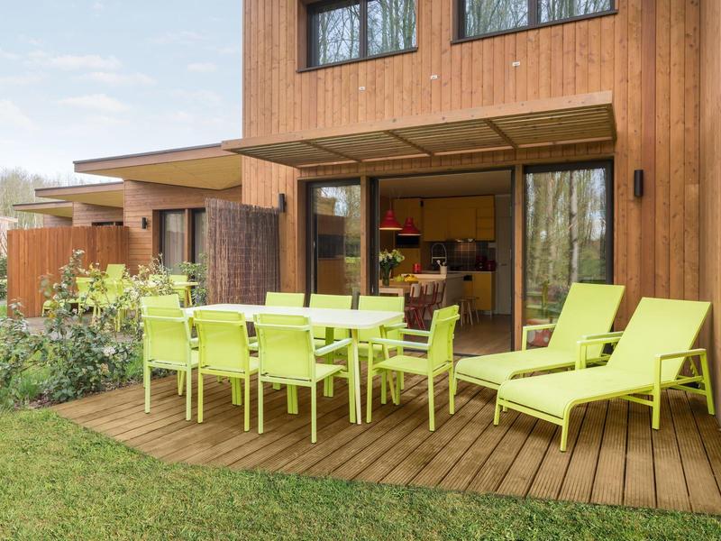 Modern terrace with a wooden house, green garden, and yellow outdoor furniture.