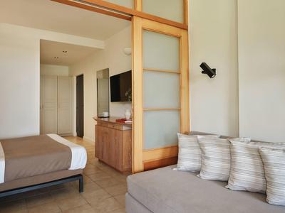 Moderner Wohnraum mit braunem Bett, Couch mit Kissen und Holzschiebetür zum angrenzenden Raum.