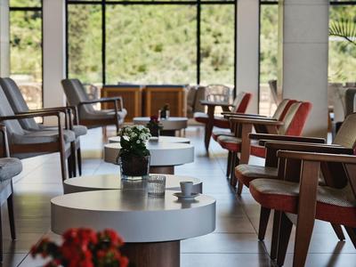 Moderne lounge met ronde tafels en gestoffeerde stoelen in een lichte ruimte.