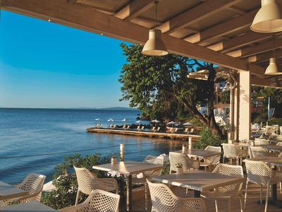 Terras van een restaurant met uitzicht op zee en een pier bij duidelijk weer.