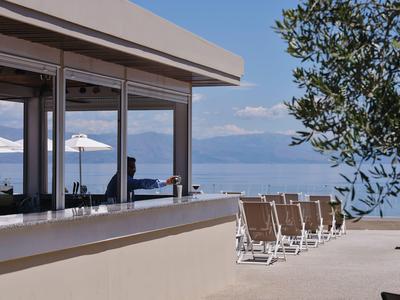 Terras met stoelen en tafels voor glasramen met uitzicht op zee en bergen.